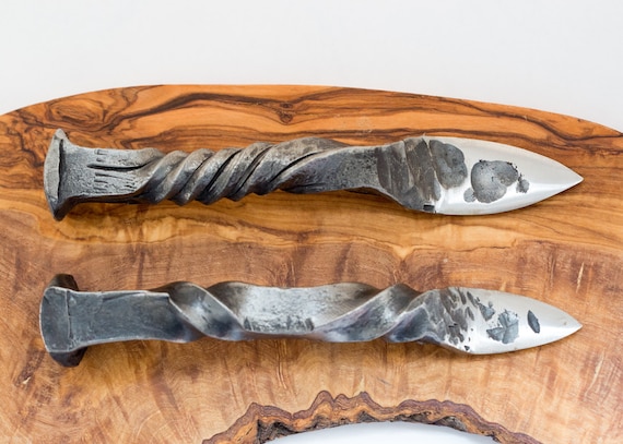 14 railroad spikes hand-forged into oyster shucker knives with built-in bottle openers — brutally functional, wildly original, and a conversation starter at every seafood boil.
