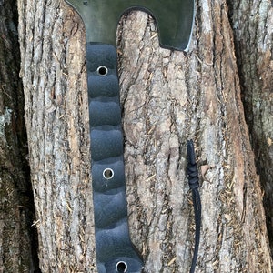 May include: A black axe with a black rubber handle and a black cord attached to the handle. The axe is resting on a tree trunk.