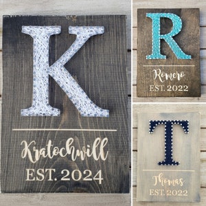 May include: Wooden string art signs featuring letters and names. The first sign has a white string "K" with "Kratochwill EST. 2024" below. The second sign has a turquoise string "R" with "Romero EST. 2022". The third sign has a navy blue string "T" with "Thomas EST. 2022".