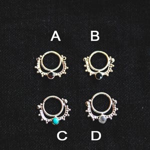 Puede incluir: Cuatro anillos de nariz de plata con piedras preciosas de diferentes colores. Los anillos están etiquetados como A, B, C y D. Las piedras preciosas son negras, negras, turquesa y blancas.