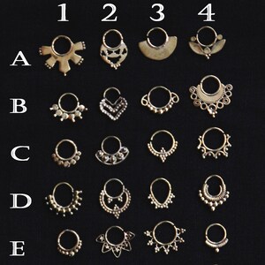May include: A set of 28 gold nose rings with different designs. The rings are arranged in rows labeled A through G and 1 through 4.