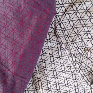 Peut inclure: Deux morceaux de tissu avec un motif géométrique. Un morceau est de couleur violet foncé avec un motif rouge, l'autre est blanc avec un motif noir.