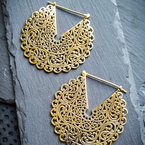 Peut inclure: Deux boucles d'oreilles dorées avec des motifs filigranés complexes. Les boucles d'oreilles ont la forme de demi-cercles et présentent un motif délicat et orné.