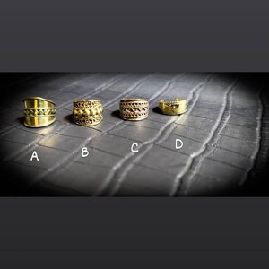 Peut inclure: Quatre boucles d'oreilles en or avec des motifs différents. Les boucles d'oreilles sont disposées en rangée de gauche à droite, étiquetées de A à D.