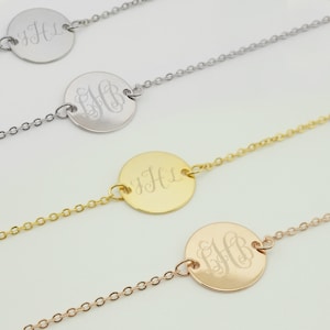 May include: Three delicate necklaces with round pendants featuring engraved initials. The necklaces are in silver, gold, and rose gold.