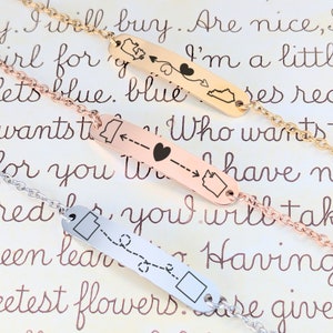 May include: Three gold, rose gold, and silver bracelets with a state outline and arrow design. The bracelets have the text "I will buy. Are nice, girl for I'm a little lets blue. blue ses rec wants ti Who wants for you have n red, you will tak een lear N eetest flowers are give" on them.