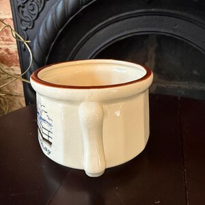 May include: A white ceramic mug with a black handle and the text "But First, Coffee" in a bold, black font. The mug is set against a blurred background, suggesting a cozy setting. The mug appears to be approximately 4 inches tall.