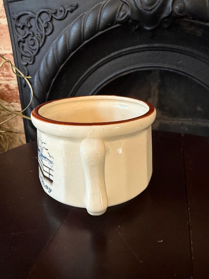 May include: A white ceramic mug with a black handle and the text "But First, Coffee" in a bold, black font. The mug is set against a blurred background, suggesting a cozy setting. The mug appears to be approximately 4 inches tall.