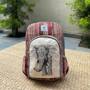 May include: A red, white, and brown striped backpack with a large elephant graphic on the front. The backpack has a black zipper and a small green leaf logo with the text "Hemp Tribe" on the top flap.