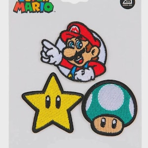 May include: A set of three embroidered iron-on patches on a display card featuring the Super Mario logo. The patches include a circular Mario character, a yellow star with black eyes, and a green and white spotted mushroom with black eyes.