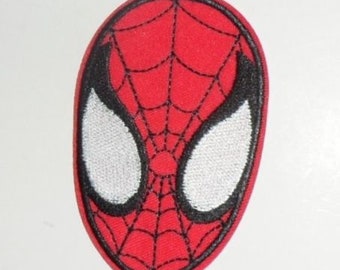 May include: A red, oval-shaped patch featuring the face of Spider-Man. The design includes white eye shapes outlined in black, and a black web pattern over a red background. The patch is likely for clothing or accessories.