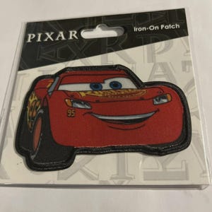 May include: An iron-on patch featuring Lightning McQueen from the Pixar Cars movie. The patch is red with black accents and the number 95. The packaging includes the Pixar logo and the words "Iron-On Patch".