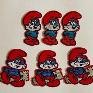 May include: Six embroidered patches featuring a cartoon character with blue skin, a red hat, and red pants. The top three patches show the character standing, while the bottom three show the character holding a light-colored, star-shaped object.