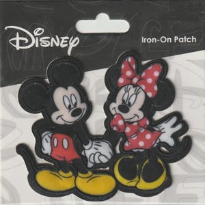May include: Iron-on patch featuring Mickey Mouse and Minnie Mouse. Mickey is wearing red shorts and yellow shoes, while Minnie is in a red polka-dot dress and bow. The Disney logo is at the top left.