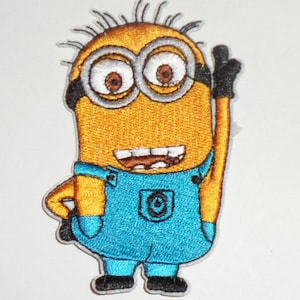 May include: Embroidered patch featuring a yellow Minion character with two eyes, wearing blue overalls. The Minion is giving a thumbs-up gesture. The patch has a white background and is likely for clothing or accessories.