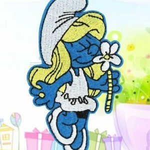 May include: Embroidered patch featuring a blue cartoon character with blonde hair and a white hat and dress. The character is holding a white flower with a yellow stem. The patch has a white border.