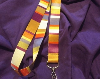 May include: A yellow, orange, purple, and blue striped lanyard with a silver swivel clip.