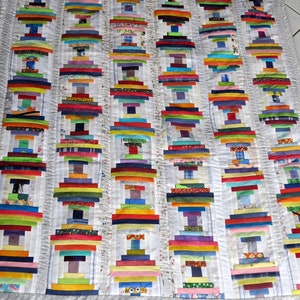 May include: A white quilt with a patchwork design featuring colorful strips of fabric arranged in a stacked pattern. The quilt is made with a variety of fabrics, including stripes, solids, and prints.