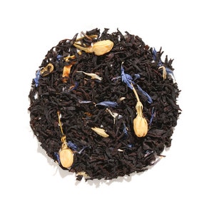 May include: A close-up of a blend of black tea leaves, blue cornflower petals, and dried jasmine flowers.