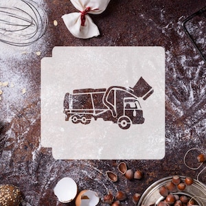 Może przedstawiać: Biały szablon ciężarówki śmieciarki na brązowym tle z rozsypaną mąką. Szablon służy do wycinania ciasteczek lub innych wypieków.