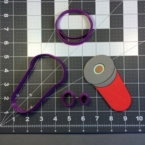 May include: A set of five purple plastic cookie cutters. The cutters are shaped like a flashlight, a circle, a ring, and two different sized ovals. The cutters are on a gray grid background.