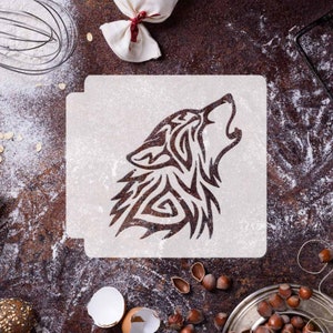 May include: A white stencil featuring a tribal wolf design. The stencil is on a brown surface with flour and other baking ingredients.