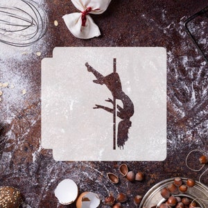 May include: A white stencil featuring a silhouette of a person on a pole. The stencil is on a brown surface with flour scattered around it.