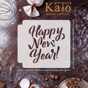 以下が含まれることがあります： 装飾的な手書きのフォントで「Happy New Year!」と書かれた白いプラスチック製のステンシル。ステンシルは、小麦粉、卵、ナッツなどの製菓用品が置かれた茶色の表面の上に置かれています。