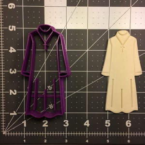 May include: Two cookie cutters, one purple and one white, shaped like a robe with a cross on the collar. The purple cutter is 3 inches tall and the white cutter is 4.5 inches tall.