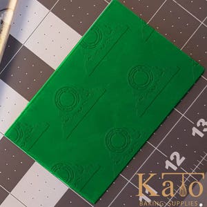 May include: A green silicone baking mat with a repeating pattern of a circle with a decorative design. The mat is designed for use with fondant and other edible decorations.