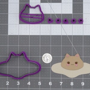 Pode incluir: Cortadores de biscoitos de plástico roxo em forma de gato, disco voador e triângulo. Há também cinco pequenos cortadores redondos.