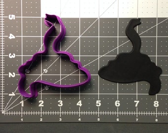 May include: Purple plastic cookie cutter shaped like a swan. The cutter is on a gray gridded surface.