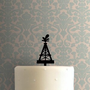 May include: Black cake topper featuring an oil derrick design. The topper is a silhouette with a detailed structure and a decorative top element. Perfect for a themed celebration.