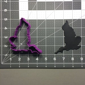 May include: Purple and black plastic cookie cutters shaped like the outline of Great Britain.