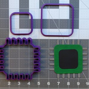 May include: Three purple plastic cookie cutters in the shape of a square, a smaller square, and a computer chip. The computer chip cutter has a detailed design with a series of small squares around the edge.