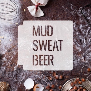 May include: A rustic, overhead shot featuring the text "MUD SWEAT BEER" stenciled on a flour-dusted surface. Baking tools, a small bag tied with a red ribbon, and hazelnuts are scattered around the text, suggesting a culinary theme.