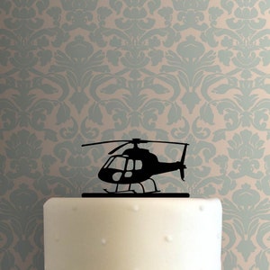 May include: Black silhouette of a helicopter cake topper. The helicopter has a single rotor and a small tail rotor. The topper is made of a thin, durable material and is perfect for adding a unique touch to any cake.