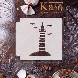 May include: A white plastic stencil of a lighthouse with birds flying around it. The stencil is on a brown surface with a ruler marked in inches. The text "Kato Baking Supplies" is at the top of the image.