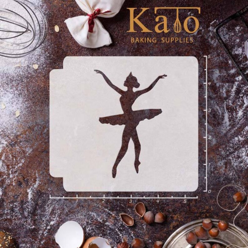 May include: A white stencil of a ballerina silhouette with a tutu, standing on a white surface with a ruler marked in inches.
