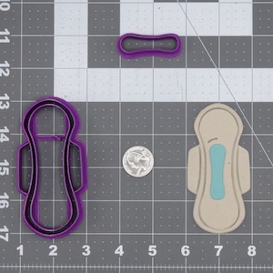 Könnte beinhalten: Ein Satz mit drei violetten Keksausstechern in Form von Damenbinden. Die Ausstecher befinden sich auf einem grauen Gitterhintergrund.