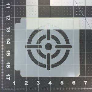 May include: A white stencil with a black target design. The target has a bullseye in the center and four concentric circles.