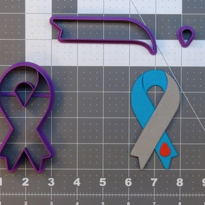 May include: Three cookie cutters in the shape of awareness ribbons. The first is purple, the second is teal and gray with a red drop, and the third is a purple banner.