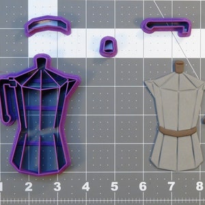 May include: A set of four purple and brown plastic cookie cutters shaped like a coffee pot. The cutters are on a grey grid background.