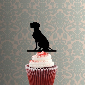 Può includere: Silhouette nera di un cane seduto su una mensola, sopra un cupcake di velluto rosso con glassa bianca e spruzzi rossi. Lo sfondo presenta una carta da parati a motivi nei toni del blu e beige.
