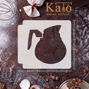 Puede incluir: Un esténcil de plástico blanco con un diseño de jarra, perfecto para hornear. El esténcil está sobre una superficie marrón con harina, nueces y utensilios de repostería. El texto "Kato Baking Supplies" es visible.