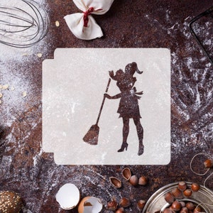 May include: A white stencil with a silhouette of a woman holding a broom. The stencil is on a brown surface with flour scattered around it.