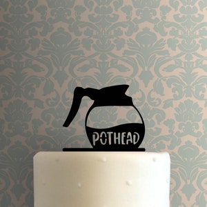 May include: Black silhouette of a coffee pot with the text "POTHEAD" on a white cake.