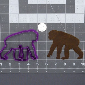 May include: Purple plastic cookie cutter in the shape of a walking ape. A brown metal cookie cutter in the shape of a walking ape is shown next to it.