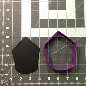 Może przedstawiać: Fioletowa plastikowa foremka do ciasteczek w kształcie pięcioramiennej gwiazdy, obok czarnego wycięcia z fondantu w tym samym kształcie.