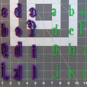 Puede incluir: Un juego de cortadores de galletas con forma de alfabeto en dos colores: morado y verde. Los cortadores están dispuestos en orden alfabético en una cuadrícula.